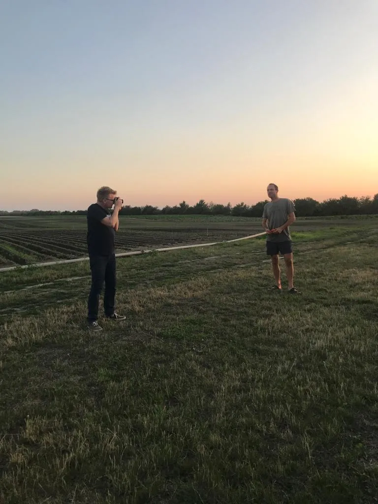 Wolfgang Lehner fotografiert einen Landwirt auf dem Feld des Biohofs ADAMAH im Abendlicht