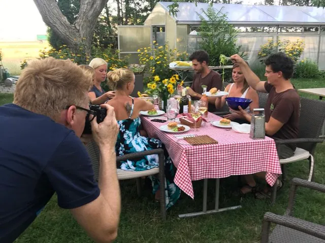 Wolfgang Lehner fotografiert kniend eine Tischrunde im Garten des Biohofs ADAMAH