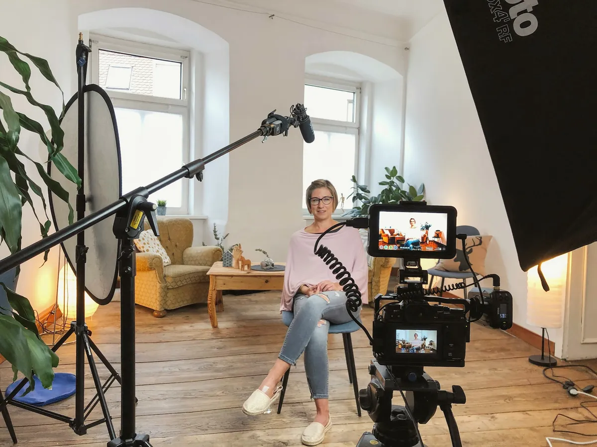 Interview-Set mit Kamera, Monitor, Mikrofon und Reflektor, eine Frau sitzt im Sessel