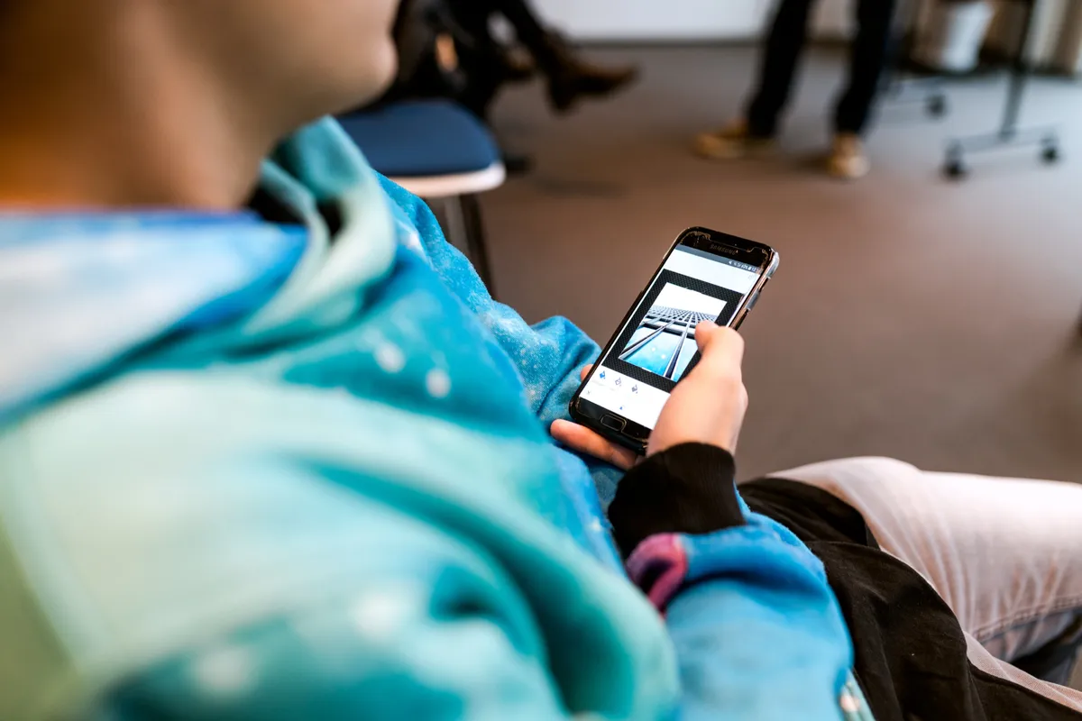 Teilnehmer hält das Smartphone und prüft eine Aufnahme im Workshop