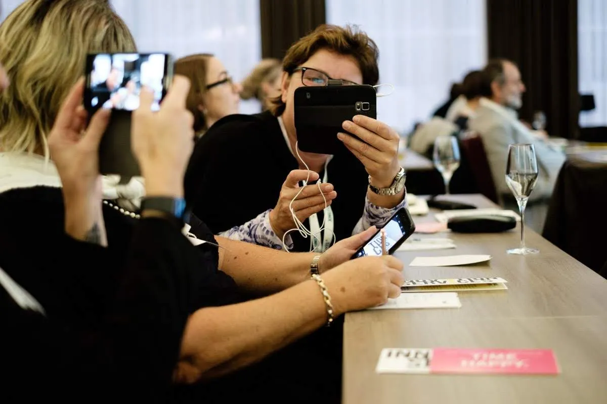 Teilnehmende filmen und fotografieren im Seminarraum mit dem Smartphone