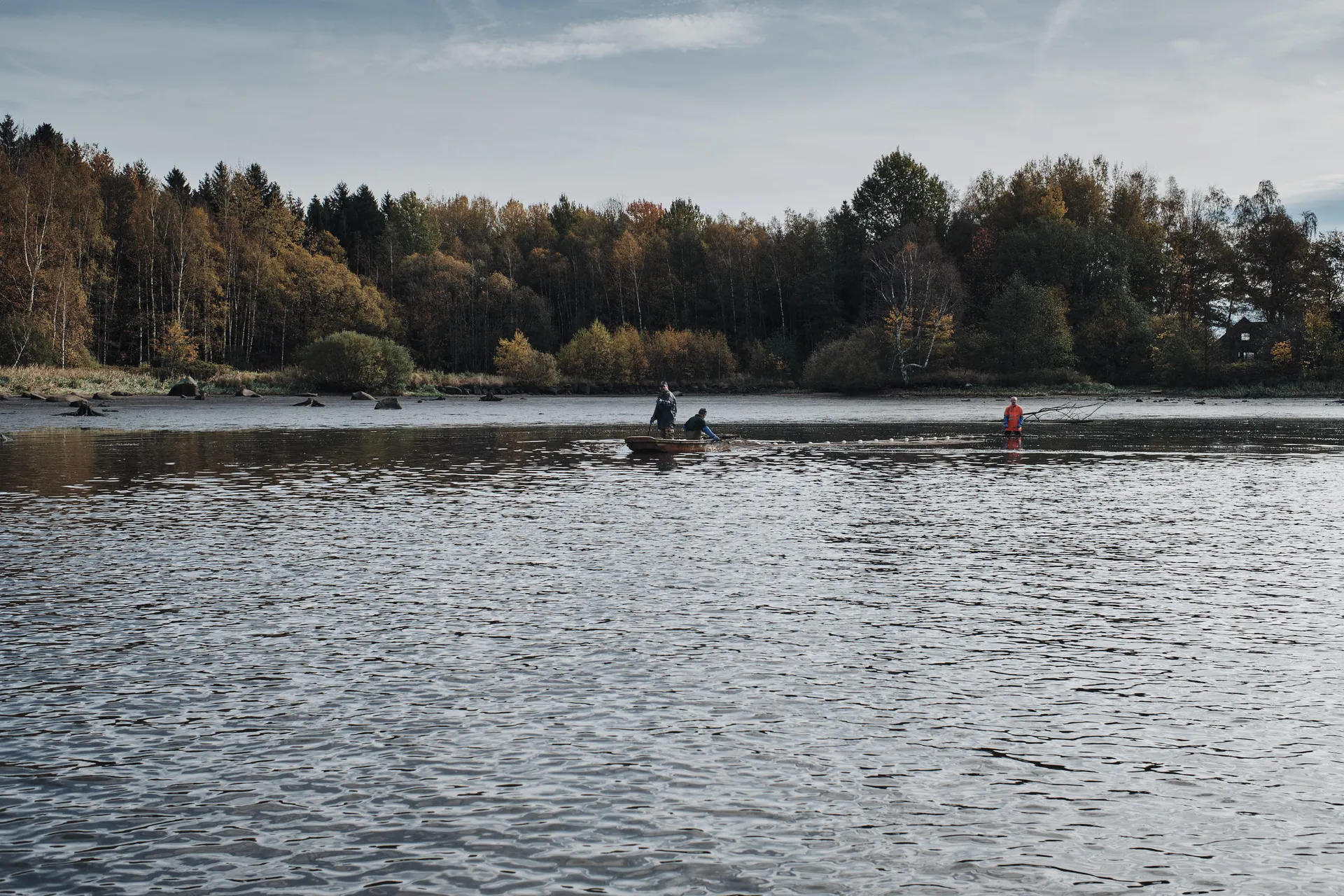 Weiter Blick über den herbstlichen Teich im Waldviertel, ein Boot und Fischer weit draußen im ruhigen Wasser.