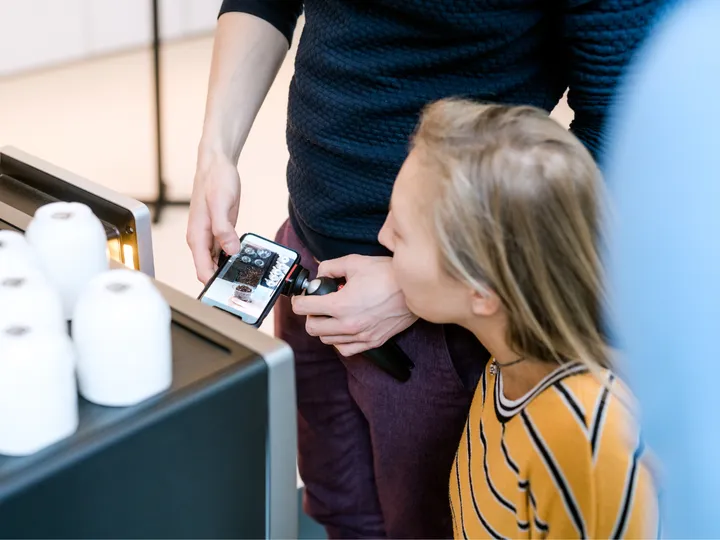 Teilnehmerin filmt mit dem Smartphone auf einem Stativ, angeleitet im Workshop